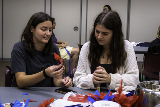 Two volunteers work together to make cat toys.